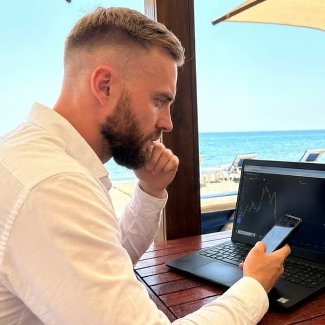 Ethan trading on a laptop by the sea